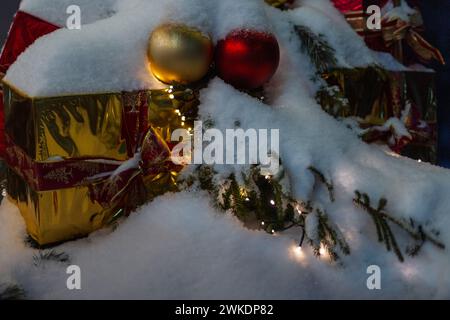 Geschenke mit Kugeln mit Lichtern im Schnee bei Nacht. Weihnachts- und Neujahrskarte. Weihnachtsbaum Stockfoto