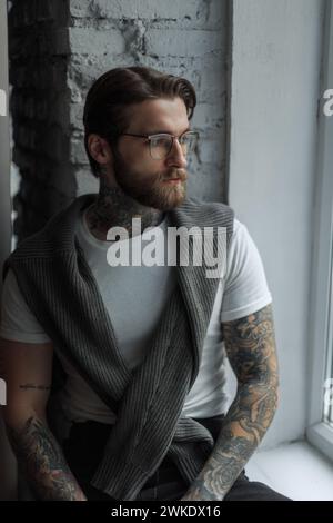 Schöner erfolgreicher junger Geschäftsmann Hipster-Mann mit Bart, Schnurrbart und Frisur mit Einem Tattoo mit Fashion Brille in Einem weißen T-Shirt mit Einem kN Stockfoto