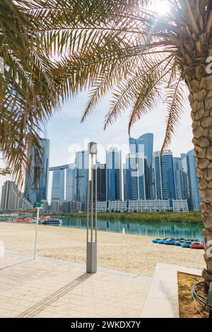 Wunderschöner Strand mit SUP-Boards, Palmen und moderner Stadtlandschaft in Abu Dhabi Stockfoto