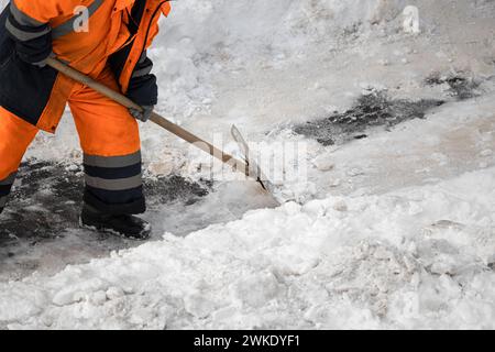 Ein Mann mit einer Schneeschaufel reinigt im Winter Gehwege. Winterzeit. Mann, der Schnee mit einem Schaber reinigt Stockfoto