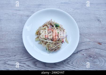 Hacken Sie unreife Mango mit trockenen Garnelen und Chili Thai Salat auf Teller Stockfoto