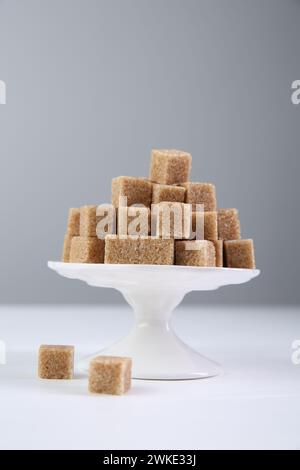 Braune Zuckerwürfel auf weißem Tisch vor hellem Hintergrund Stockfoto