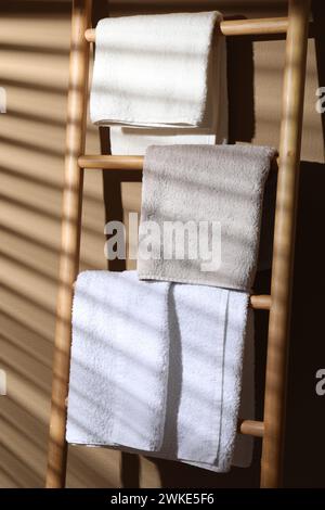 Frotteetücher auf einer dekorativen Holzleiter in der Nähe der beigefarbenen Wand Stockfoto