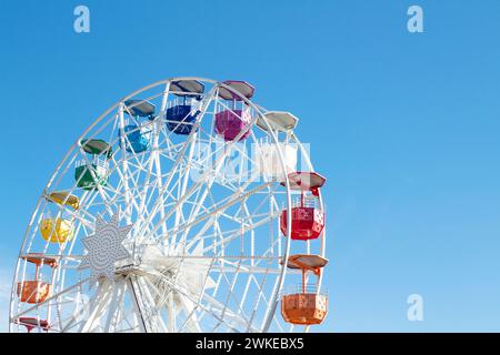 Riesenrad mit mehrfarbigen Fahrerhäusern auf blauem Himmel Stockfoto