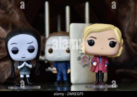 Funko Pop Actionfiguren von Wednesday Addams, Serienmörder Michael Myers von Halloween und Sabrina Spellman. Säulen, dunkle Krypta, weißer Sarg Stockfoto