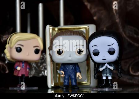 Funko Pop Actionfiguren von Sabrina Spellman, Serienmörder Michael Myers von Halloween und Wednesday Addams. Säulen, Reflektionsboden, weiße Tür. Stockfoto