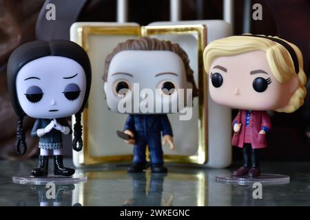 Funko Pop Actionfiguren von Wednesday Addams, Serienmörder Michael Myers von Halloween und Sabrina Spellman. Säulen, dunkle Krypta, weißer Sarg Stockfoto