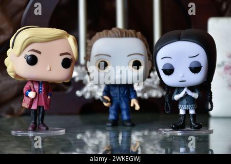 Funko Pop Actionfiguren von Sabrina Spellman, Serienmörder Michael Myers von Halloween und Wednesday Addams. Säulen, Reflektionsboden, weiße Tür. Stockfoto