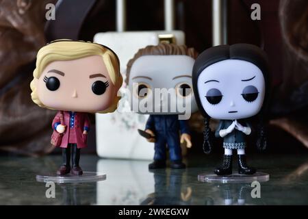 Funko Pop Actionfiguren von Sabrina Spellman, Serienmörder Michael Myers von Halloween und Wednesday Addams. Säulen, Reflektionsboden, weiße Tür. Stockfoto