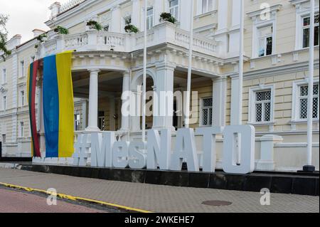 Jan Schmidt-Whitley/Le Pictorium - Illustrationsbilder Litauens - 19/02/2024 - litauen/Baltische Länder/Vilnius - Eine litauische Flagge und eine ukrainische Flagge sind auf dem Giebel des litauischen Verteidigungsministeriums zu sehen; zusammen mit dem Hashtag Nous Sommes l’OTAN (#MesNato) zeigt das Äquivalent des französischen Militärministeriums seine Unterstützung für die ukrainische Sache. Dies folgt auf den NATO-Gipfel, der 2023 in Vilnius stattfand. Angesichts der Gefahren einer russischen Invasion zeigt die litauische Regierung ihre Verbundenheit mit den schützensfähigen Organisationen Stockfoto