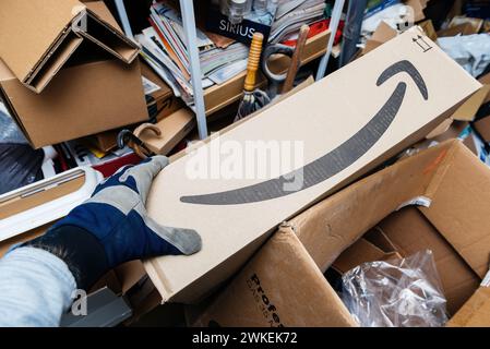 Bremen, Deutschland 10. Dezember 2023: Männliche Hand holt Amazon Prime-Paket während der allgemeinen Reinigung aus einer unordentlichen Garage. Stockfoto