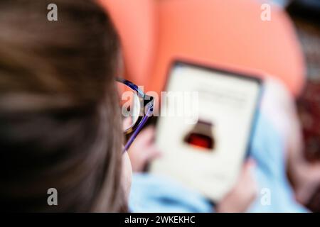 London, Großbritannien - 13. September 2023: CA Ca Curious Woman blickt auf ihr Tablet, ihr Fokus wird von der Brille erfasst, die sie trägt Stockfoto