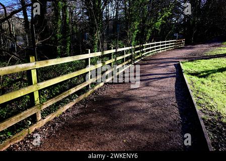 Ein Zaun neben einem gemeinsamen Fußweg/Radweg, sonnig vom niedrigen Sonnenwinkel im Winter. Stockfoto