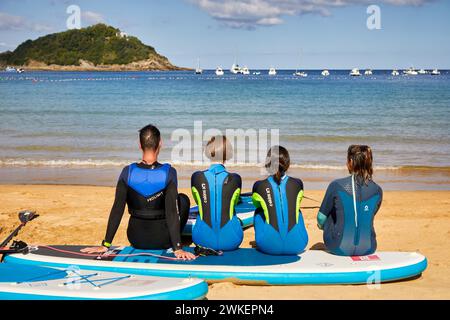 Gruppe von Touristen ruhte sich am Strand aus, Paddelsurfen in der Bucht von La Concha, SUP, Stand Up Paddle, Donostia, San Sebastian, Baskenland, Spanien Stockfoto