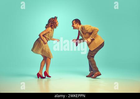 Dynamisches Porträt eines attraktiven Paares in Retro-Kleidung tanzender Boogie-Woogie vor verlaufendem mintfarbenen Hintergrund. Stockfoto