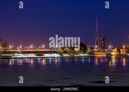 Blick auf den ab Dambis von Riga, während der blauen Stunde einer Winternacht. Der Fernsehturm hebt sich in der Skyline hervor Stockfoto