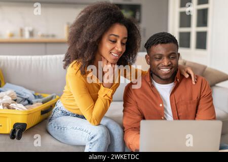 Schwarze Ehepartner buchen Flüge und Hotels online mit Laptop-Indoor Stockfoto