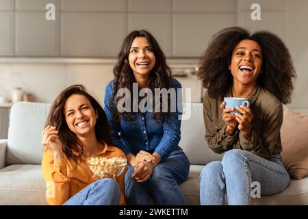 Drei internationale Freundinnen versammeln sich auf dem Sofa im Wohnzimmer Stockfoto