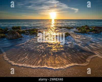 Kleine Wellen, die am felsigen Strand des Golfs von Mexiko am Caspersen Beach bei Sonnenuntergang in Venice Florida USA auftauchen Stockfoto