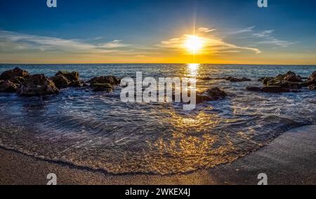 Kleine Wellen, die am felsigen Strand des Golfs von Mexiko am Caspersen Beach bei Sonnenuntergang in Venice Florida USA auftauchen Stockfoto