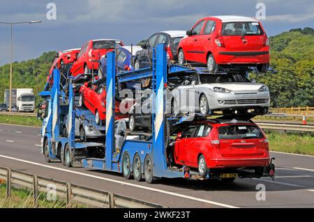 Pkw-Transporter LKW-Lkw-Großmobil und Sattelanhänger beladen mit neuen Autos, die auf der M25-Kreisautobahn Essex England Großbritannien fahren Stockfoto