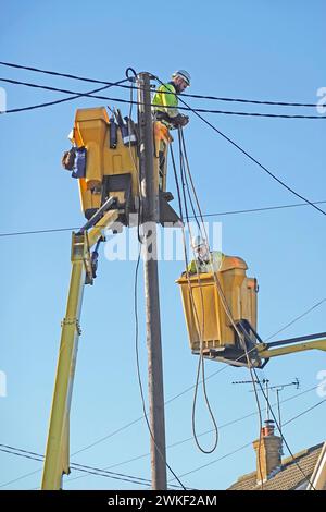 Elektroingenieure, die in Wohngebäuden arbeiten, die am Wintertag des blauen Himmels in England Großbritannien die Oberleitungen ersetzen Stockfoto