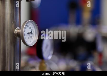 Thermometeranzeige und Warmwasserbereiter in einem Kesselraum. Selektiver Fokus. Stockfoto