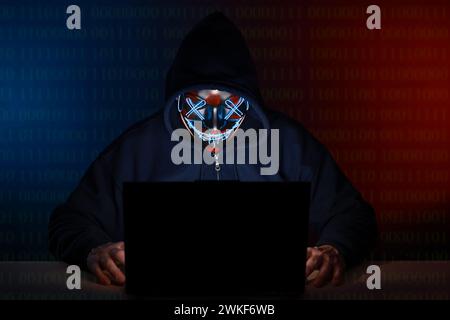 Black hat Hacker mit Maske und Hoodie-Konzept an einem Laptop, der das Internet hackt. Cyberkriminalität und Sicherheitsgrundsätze. Stockfoto
