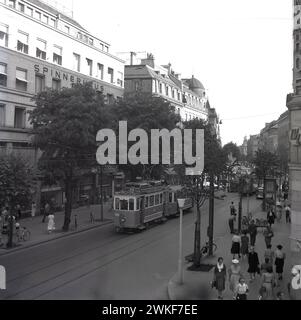 1960er Jahre, historische Straßenszene, mit Menschen und einer Straßenbahn auf der von Bäumen gesäumten Bahnhofstraße in Zürich, Schweiz. Auf dem Bild ist das Spinnerhausgebäude zu sehen. Die im Stadtzentrum gelegene Straße stammt aus dem Jahr 1864 und ist eine wichtige Verbindung zum Züricher Straßenbahnnetz. Stockfoto