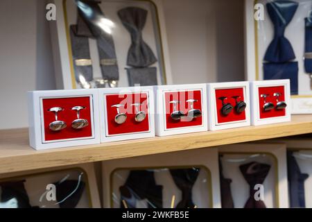 Boxen mit Manschettenknöpfen im Regal in der Boutique. Set aus schönen Manschettenknöpfen aus Platin oder Gold, verschiedene Formen. Manschettenknöpfe in Holzkisten auf schwarzem Samt pa Stockfoto