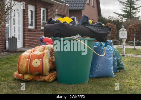 Stapel von Sperrmüll vor einem Haus mit Müllsäcken und Regenfässern Stockfoto