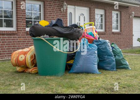 Stapel von Sperrmüll vor einem Haus mit Müllsäcken und Regenfässern Stockfoto