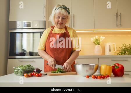 Nahaufnahme zugeschnittenes Bild eines weiblichen Schneidebretts, das Gemüse in der Küche schneidet und Mahlzeiten zuhause zubereitet. Vegetarische gesunde Ernährung Stockfoto