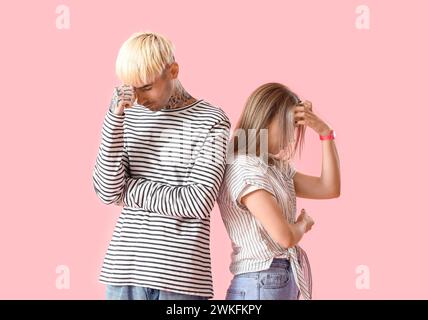 Beleidigtes junges Paar mit pinkfarbenem Hintergrund Stockfoto
