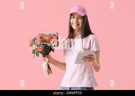 Junge Lieferfrau mit Blumenstrauß und modernem Tablet-Computer auf rosa Hintergrund Stockfoto