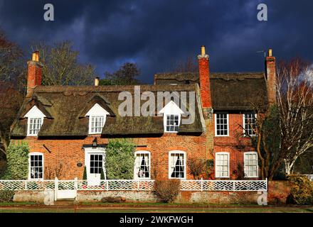 Unter einem stürmischen Himmel entlang des Flusses, der in Wainfleece All Saints in Lincolnshire fließt, steht dieses schöne reetgedeckte Häuschen. Stockfoto