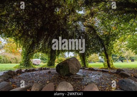 Wunderschöne grüne Kuppel aus grünen Blättern über Steinring mit riesigem Felsen in der Mitte im großen Garten Stockfoto