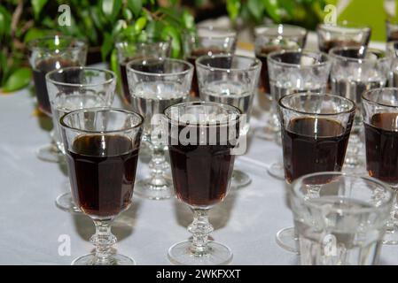 Eine Reihe von Weintrinkgeschirr gefüllt mit verschiedenen alkoholischen Getränken, einschließlich Wein und Champagner, auf einem Tisch ausgestellt. Partyvorbereitung. Stockfoto
