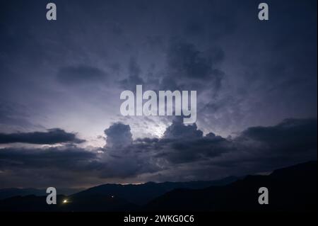 Ein abendliches Gewitter mit Blitz in den Karpaten, dem Dorf Dzembronya. Dramatische Wolken während eines Gewitters durchdringen das Licht Stockfoto