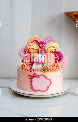 Geburtstagskuchen mit niedlichem Fondant-Einhorn, Lutscher, Baisons, Eis und Schokoladenblumen für ein Mädchen oder ein Baby. Text Alles Gute Zum Geburtstag Stockfoto