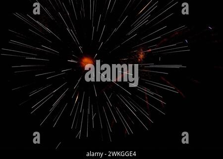 Violettes, weißes und oranges Feuerwerk am Nachthimmel. Stockfoto