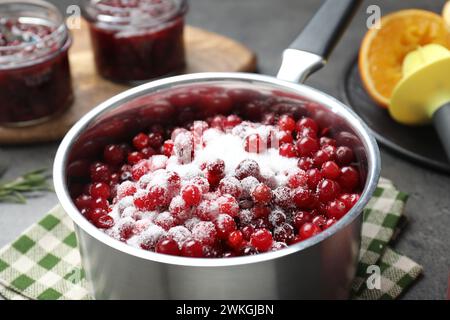 Preiselbeersauce herstellen. Frische Preiselbeeren mit Zucker in einem Topf auf dem Tisch, Nahaufnahme Stockfoto