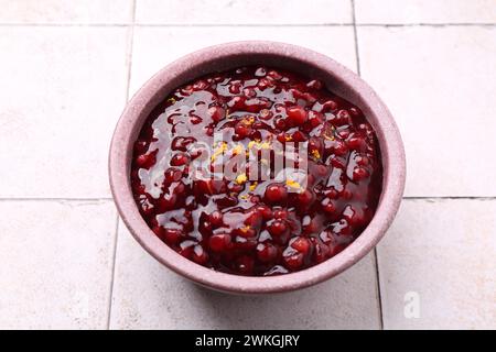 Leckere Preiselbeersauce in der Schüssel auf weißem Fliesentisch Stockfoto