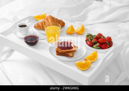 Tablett mit leckerem Frühstück auf dem Bett, Nahaufnahme Stockfoto