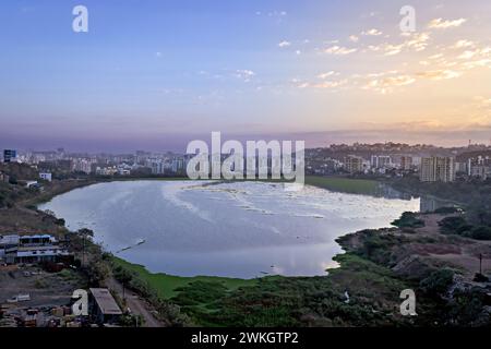 Wunderschöner Sonnenaufgang über hohen Gebäuden und Jambhulwadi See in Pune, Maharashtra, Indien. Stockfoto