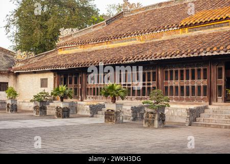 Ein ruhiger Innenhof zeigt ein klassisches vietnamesisches Haus mit einem komplizierten Fensterdesign, ornamentalen Dachziegeln und Topfpflanzen im weichen L Stockfoto