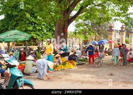 Hue City, Vietnam 21. März 2015: Frauen mit traditionellen Hüten, die bunte Blumen auf einem geschäftigen Straßenmarkt unter Sonnenschirmen verkaufen Stockfoto