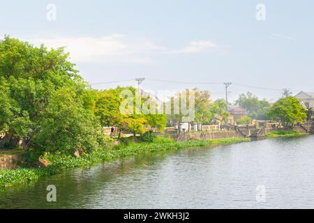 Ruhiger Blick auf den Fluss mit Dorf und üppigem Grün an einem sonnigen Tag Stockfoto