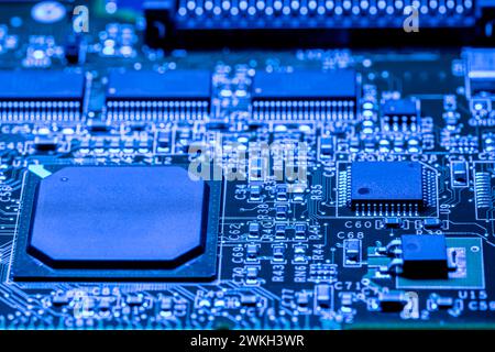 Computerplatine mit Chips und verschiedenen elektronischen Bauteilen. Blau gefärbt. Nahansicht. Stockfoto