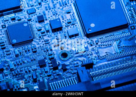 Computerplatine mit Chips und verschiedenen elektronischen Bauteilen. Blau gefärbt. Nahansicht. Stockfoto